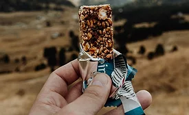 Hands holding a protein bar in the hills
