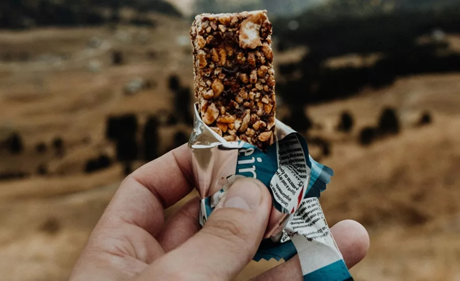 Hands holding a protein bar in the hills