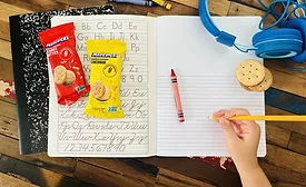 Packages of Mavericks snacks on notebook next to child's hand
