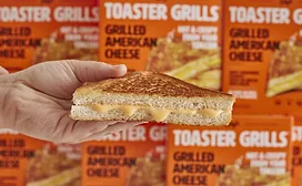 Hand holding grilled cheese in front of Lily's Toaster Grills cartons