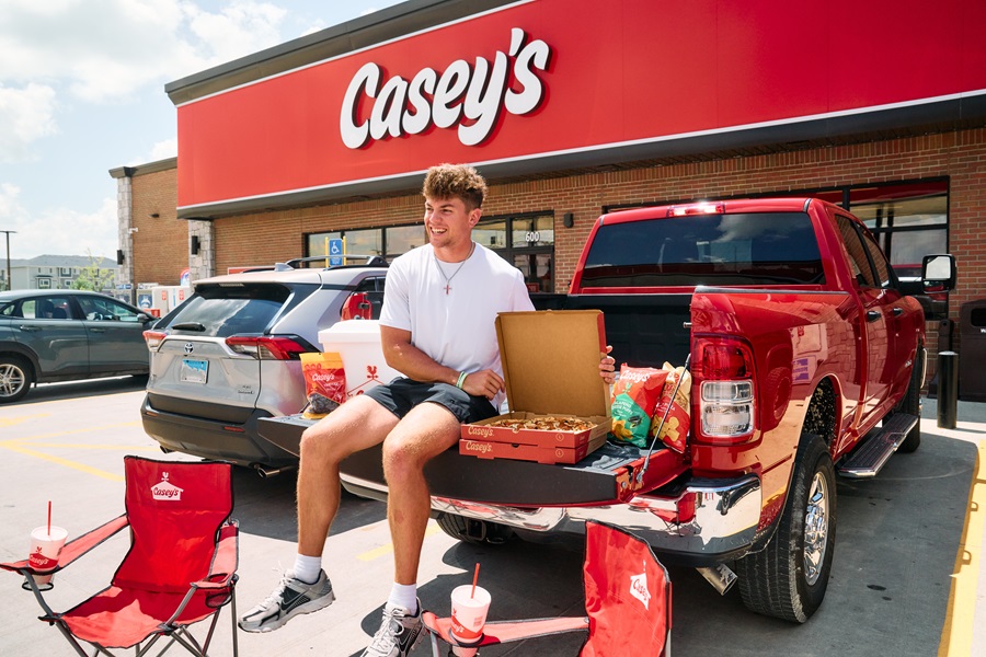 Football player Cooper DeJean eating pizza in front of Casey's
