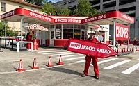 Chomps_lead.jpg Man holding red Chomps Snacks Ahead sign in front of gas station