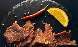 Jerky on black table with pepper and citrus