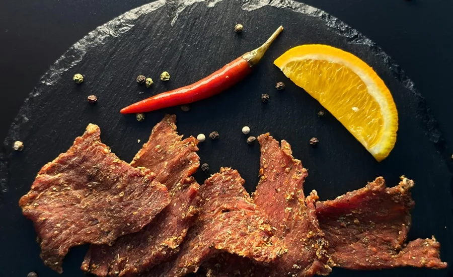 Jerky on black table with pepper and citrus