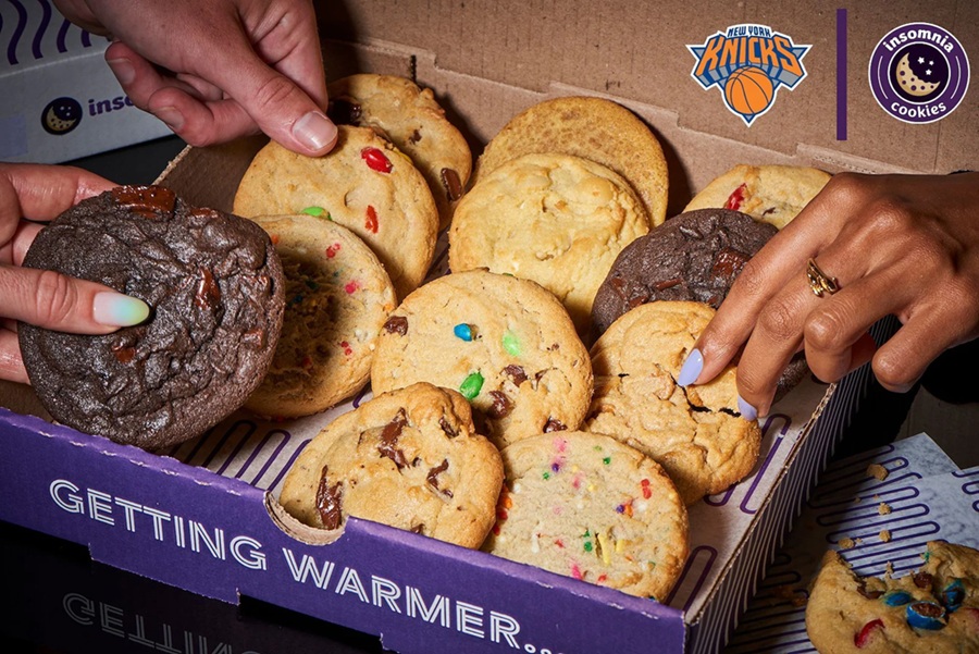 Hands reaching into box of cookies with Knicks sticker