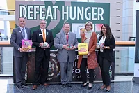 EATS_GCFD.jpg People in suits standing under DEFEAT HUNGER sign