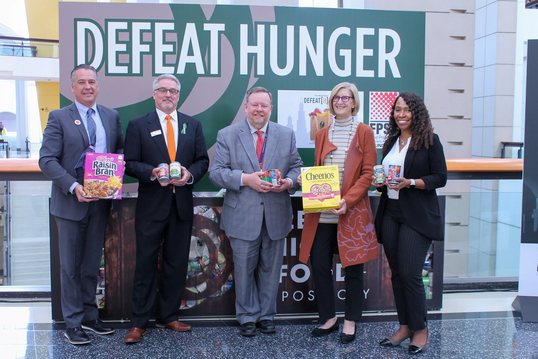 People in suits standing under DEFEAT HUNGER sign