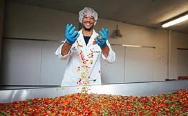 Black man playing with colorful candy in factory