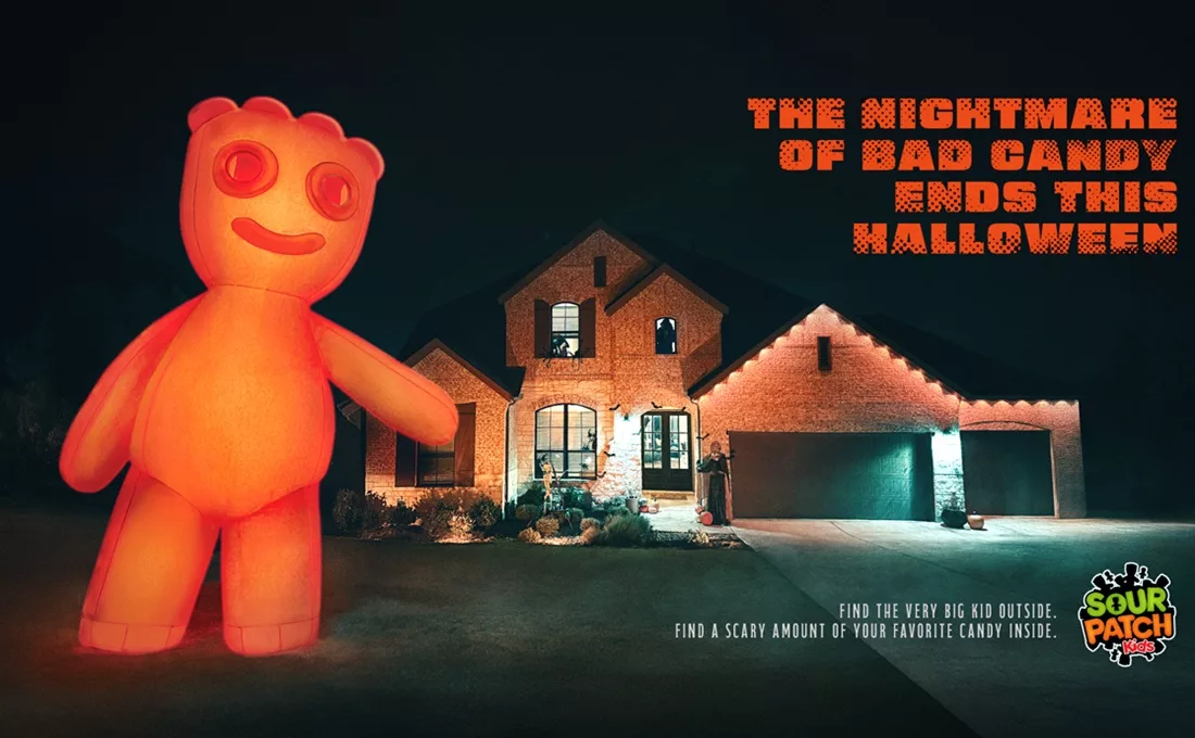 Giant inflatable Sour Patch Kid next to house at night