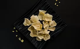 Crisps on rectangular black plate on a black table