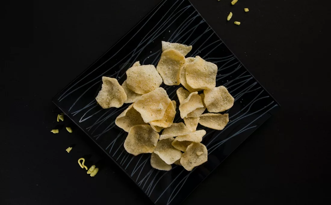 Crisps on rectangular black plate on a black table