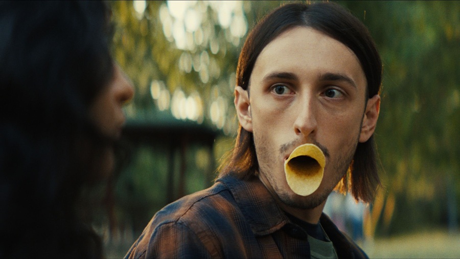 Man in park setting making duck lips with potato crisps