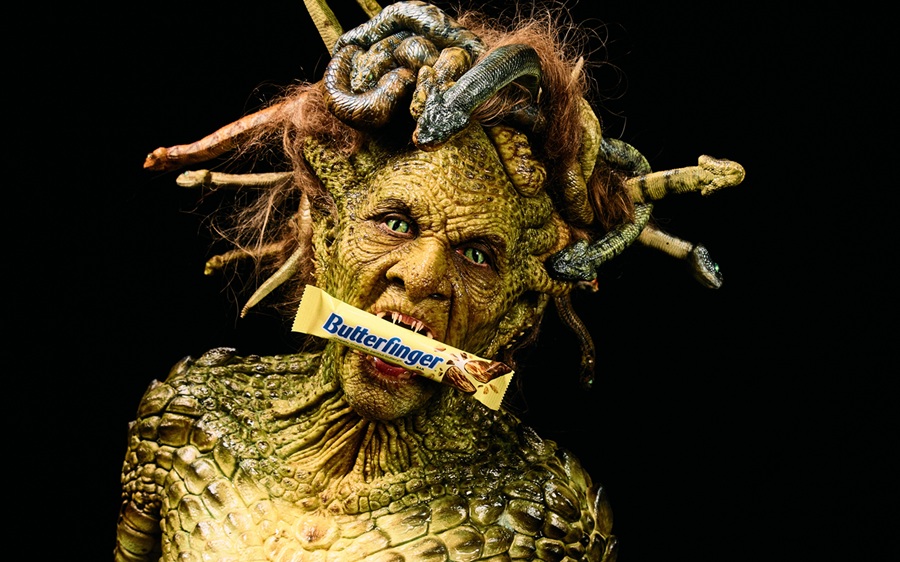 Woman dressed as Medusa holding Butterfinger in mouth