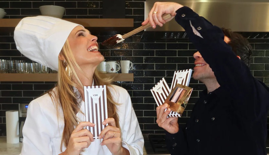 Woman holding chocolate bars as man feeds her