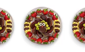 Platter of coated cookies, fruit, and other foods arranged to look like a turkey