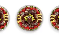 Platter of coated cookies, fruit, and other foods arranged to look like a turkey