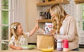 Woman in kitchen handing Perfect Bar to little girl