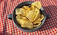 Potato chips in blue bowl on red and white tablecloth