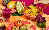 Colorful table with variety of fruit, dip, snacks, and other food