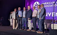 Several professionals standing on stage in front of purple background