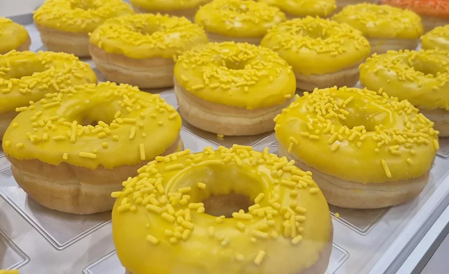 Tray of raised doughnuts with yellow sprinkles and glaze