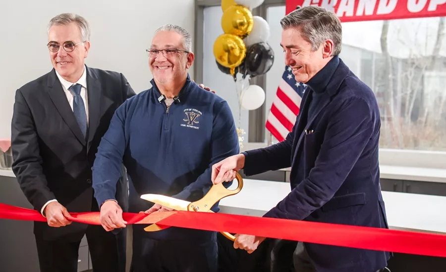 Three men smiling and cutting the ribbon at an opening ceremony