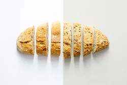 Sliced loaf of crusty bread on white and gray background