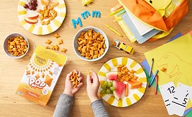 Simple Mills PopMmms crackers on a table with a child's hand and other stuff