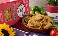 Bowl of tortilla chips on table in front of red bag
