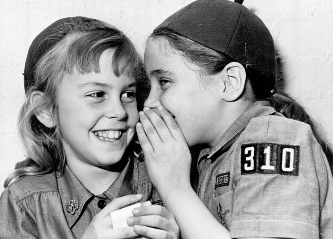 Black and white photo of two Girl Scouts telling secrets