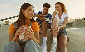 Three people eating snacks outdoors