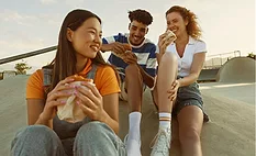 Three people eating snacks outdoors