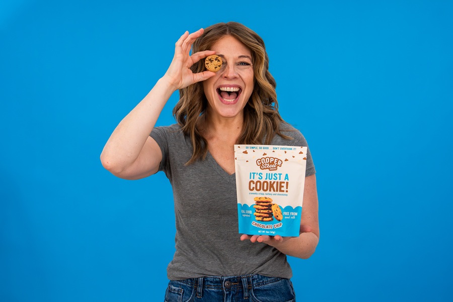 Woman holding Cooper Street cookie pouch and a cookie up to her face