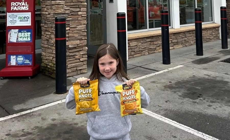 Adorable little girl in front of Royal Farms store holding two bags of Puff Knots