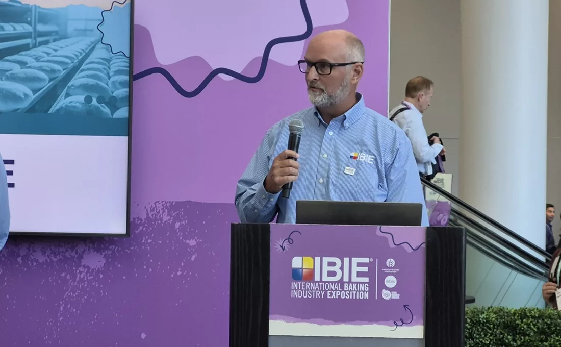 Bald, bearded white man at IBIE podium
