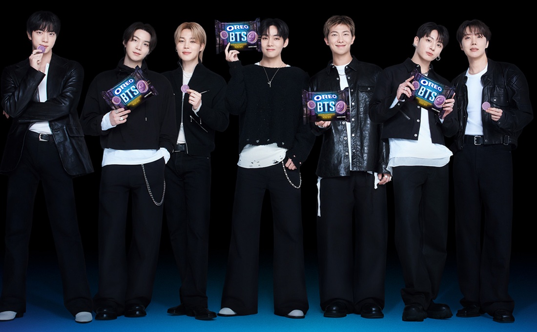 Group of attractive Korean men from BTS on black background eating Oreo cookies
