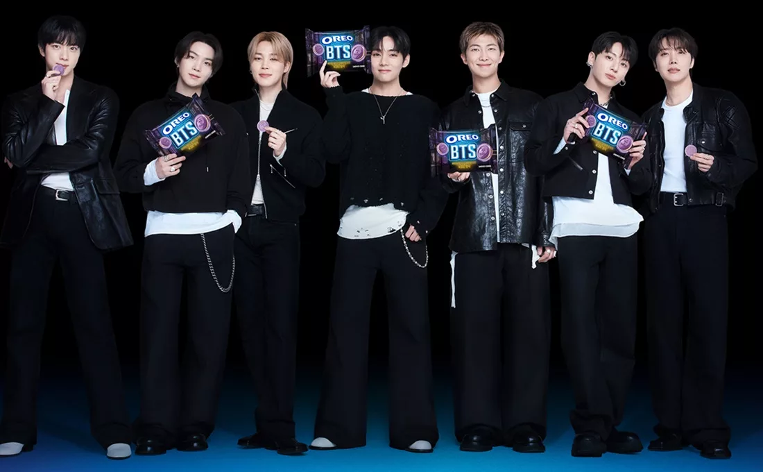 Group of attractive Korean men from BTS on black background eating Oreo cookies