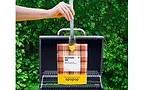 Hand holding tongs with Opopop popcorn bag over grill