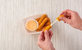Hands picking up mozzarella sticks over table