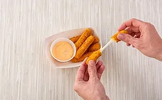 Hands picking up mozzarella sticks over table