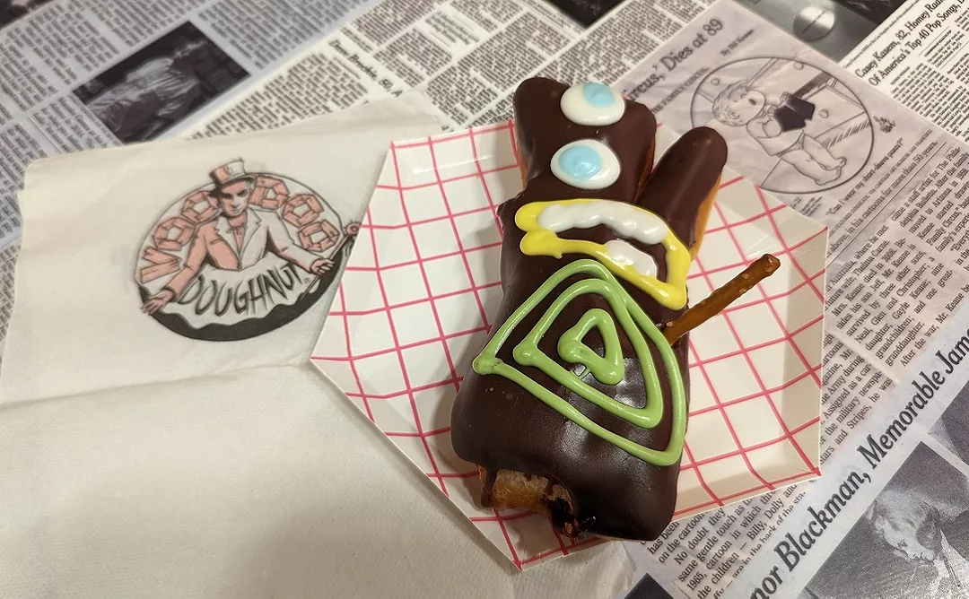 The company’s signature Voodoo Doll is a raised doughnut filled with raspberry jelly, topped with chocolate icing, and a pretzel-stick pin.