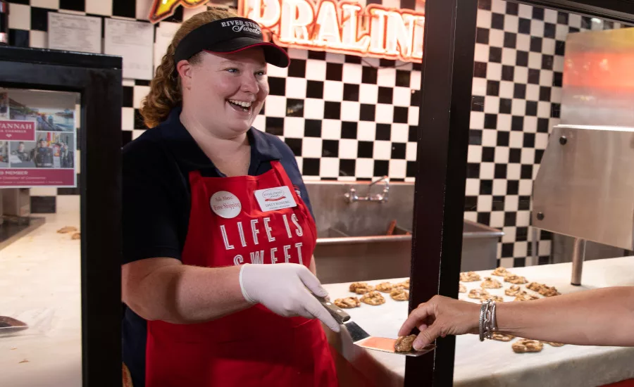 A River Street Sweets employee offers a praline sampler to a customer.