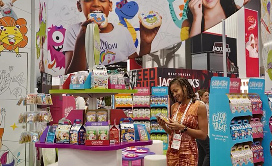 A person looking at their phone standing in a booth surrounded by colorful displays of product