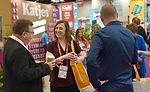 A group of people talking and smiling in front of expo booths