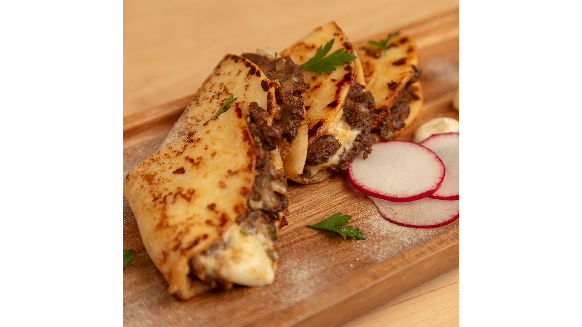Pieces of meat and cheese quesadillas on wood cutting board