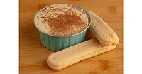 Ramekin of tiramisu next to ladyfingers on wood table Ramekin of tiramisu next to ladyfingers on wood table