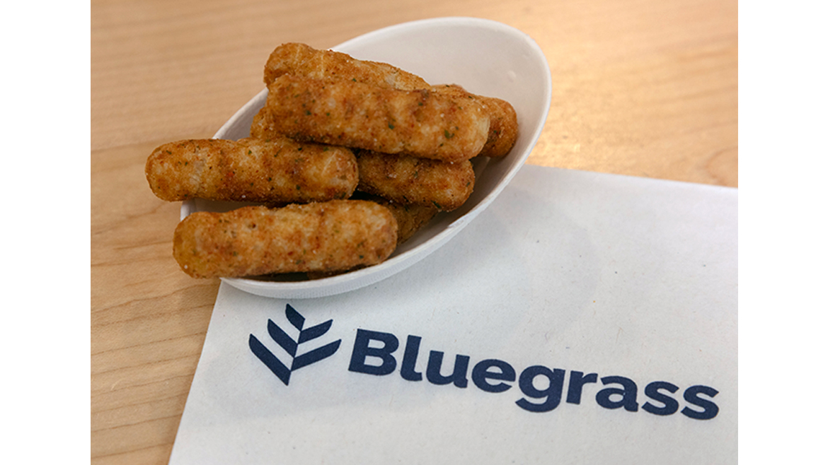 Extruded snack sticks in white bowl on top of Bluegrass Ingredients napkin