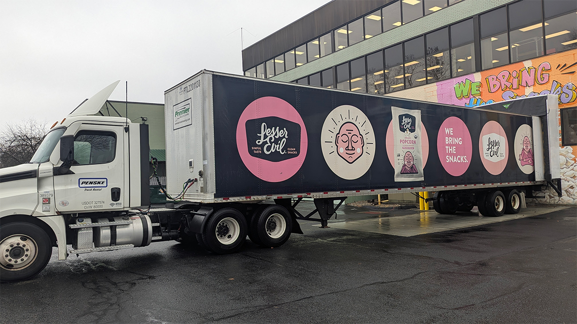a semi-truck trailer featuring large logos and branding for the LesserEvil snack company