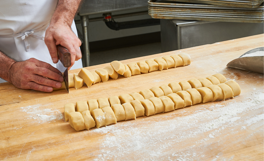 Baker cutting a slab of cookie dough into blocks