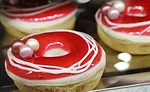 Doughnuts with a red and white frosting glaze and other confectionery items on the top.